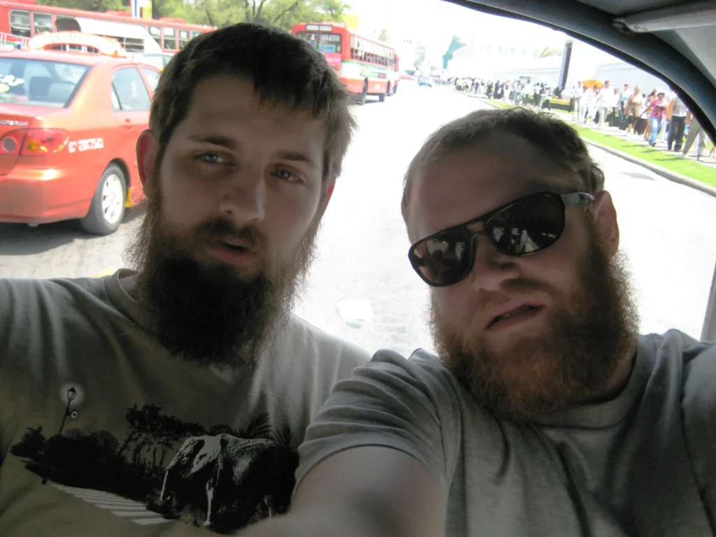 Two bearded men in a tuktuk.